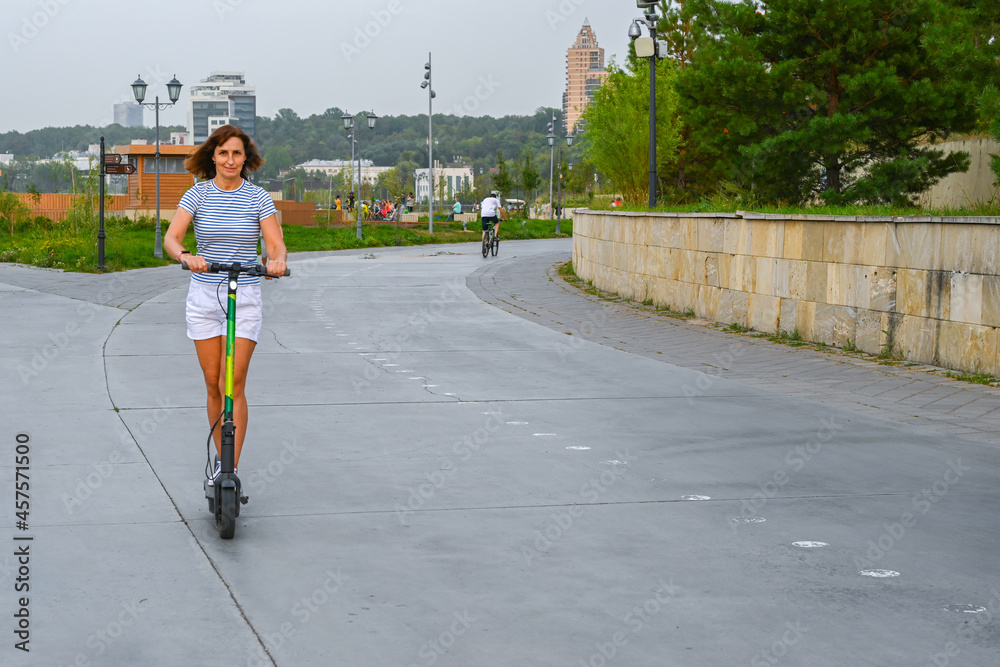 A woman rides a scooter on the Kazan embankment. Eco-friendly transport.