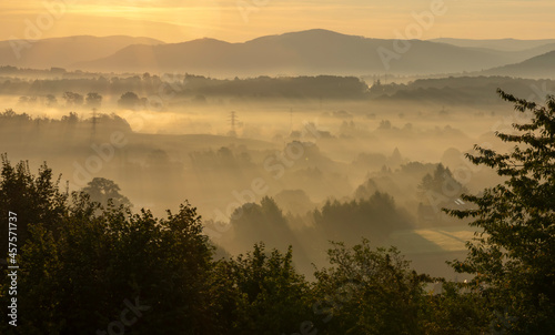 View of the valley full of fog during sunrise, with mountains in the background