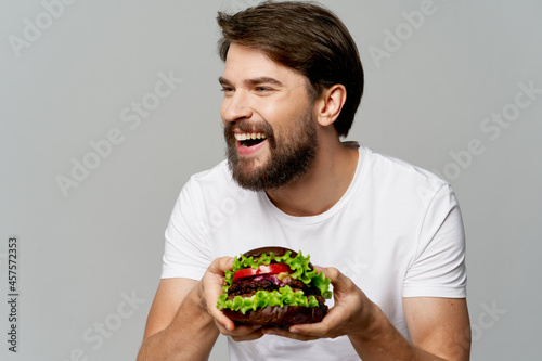 man with a plate of salad laughs and looks to the side on a gray background