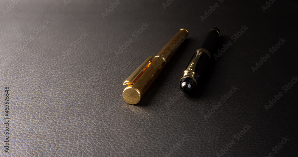 Fountain pen, beautiful details of two beautiful fountain pens placed on black leather, selective focus.
