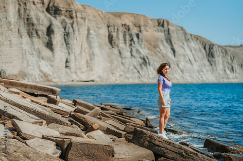 A young woman in shorts on a rocky beach made of natural stones in the Crimea, a gloomy icelandic landscape