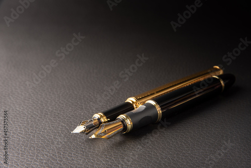 Fountain pen, beautiful details of two beautiful fountain pens placed on black leather, selective focus.