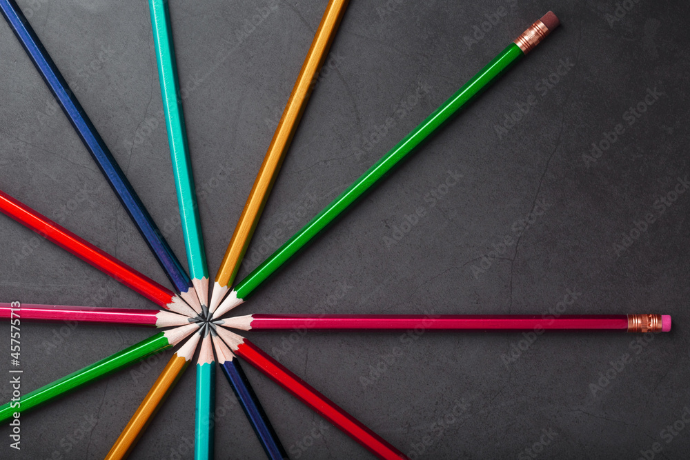 Wooden pencils of different colors in the shape of a star on a black background.