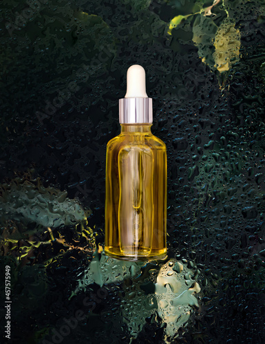 cosmetic serum bottle on natural background with water drops organic cosmetics