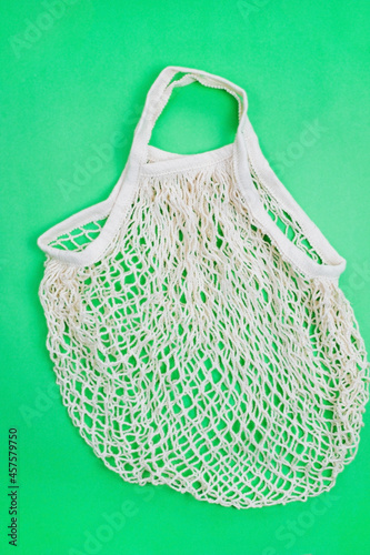 The concept of zero waste without plastic. Cotton reusable mesh shopping bag on a green background.