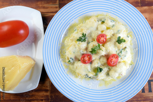 delicious gnocchi pasta in white sauce with parmesan cheese, tomato, basil, herbs, healthy food from Italian and French cuisine