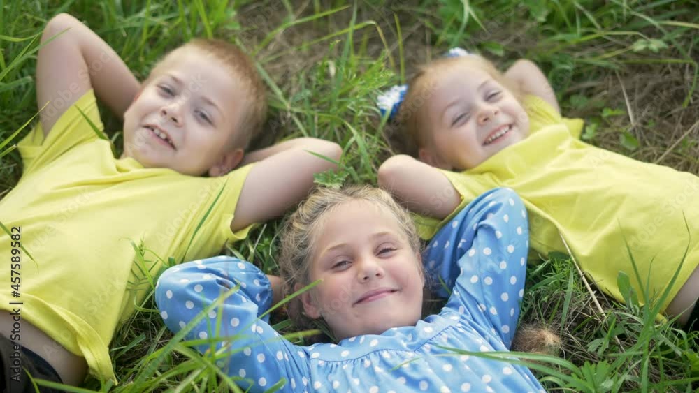 Happy child lie on green grass. Children friendship. Family is play in nature park. Happy smiles of child on green grass. Children friendship in nature park. Smiles child on grass. Family lie in park Happy child lie on green grass. Children friendship. Family is play in nature park. Happy smiles of child on green grass. Children friendship in nature park. Smiles child on grass. Family lie in park