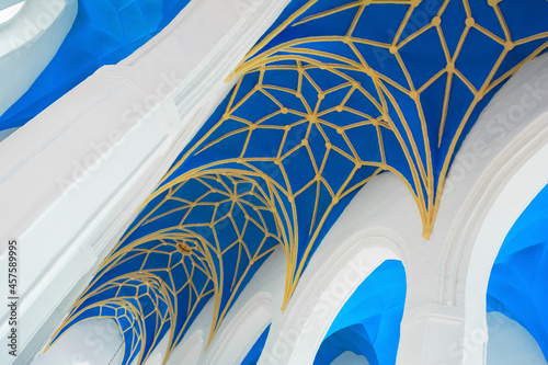 Blue and yellow ornamental church ceiling (nave) and white arches, fragment photo