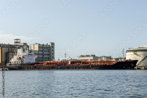 cargo ship on the river bank next to industrial facilities © Sergey