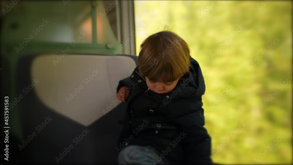 Child traveling by train, toddler passenger on a trip standing on seat Child traveling by train, toddler passenger on a trip standing on seat