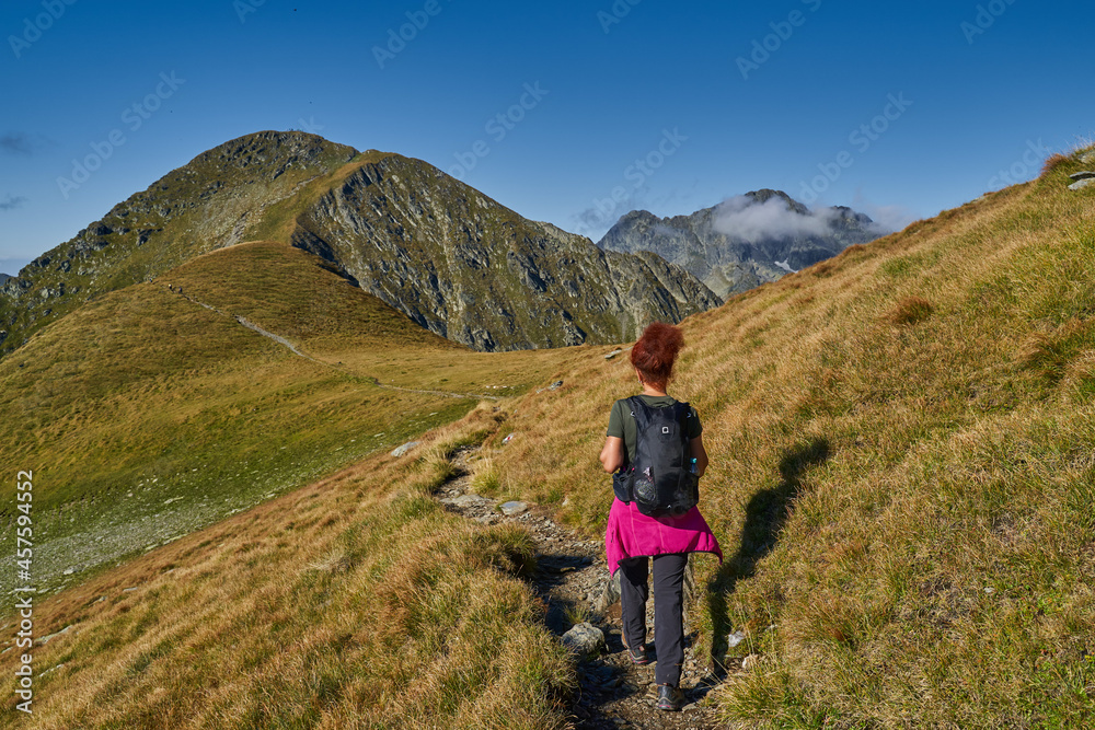 Woman hiker with backpack on a trail in the mountains