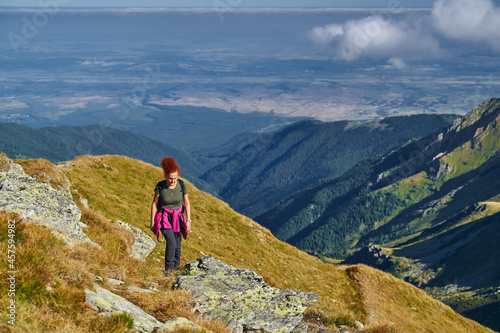 Woman hiker with backpack on a trail in the mountains