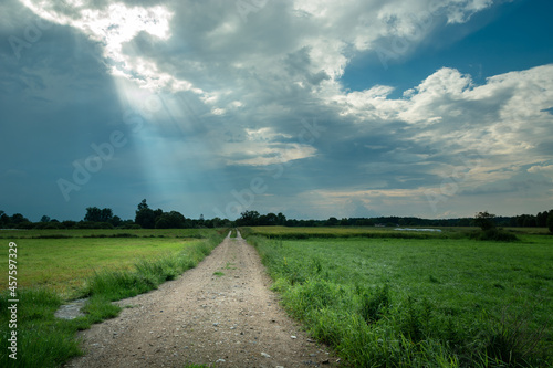 Sunbeams in the clouds and dirt road