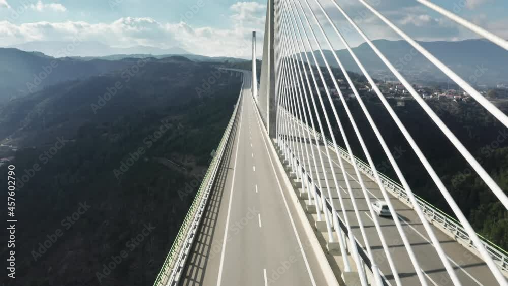 Overhead shot of autos moving fast on Vila Real Bridge, Portugal, Europe. Scenic view of vehicle building located in green mountains. Cars driving on road bridge at sunny day, 4k footage
