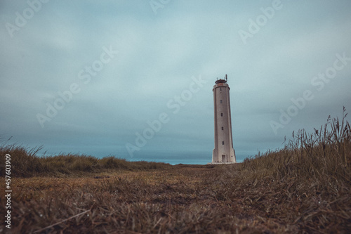 Panoramic view of Malarrif lighthouse on the east of iceland on a cloudy day. Tall Lighthouse in iceland in grey color and thick clouds above.