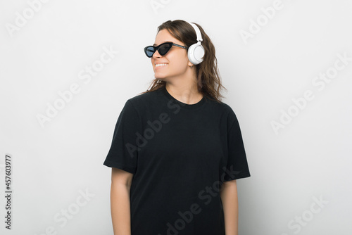 Side view portrait of a young woman wearing headphones over white background.
