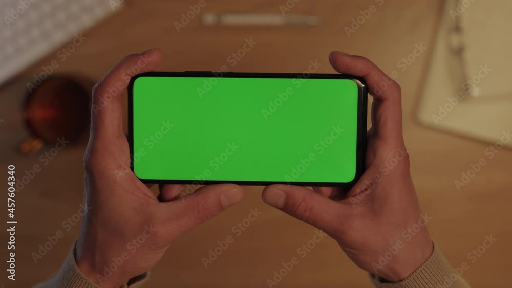 Male hands holding smartphone with green mockup screen Male hands holding smartphone with green mockup screen