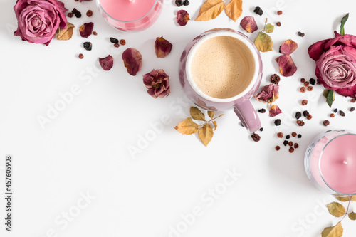 Autumn composition with cup of coffee, dry roses and candles. Autumn background in pastel colors with dried pink flowers and leaves. Flat lay, top view, copy space