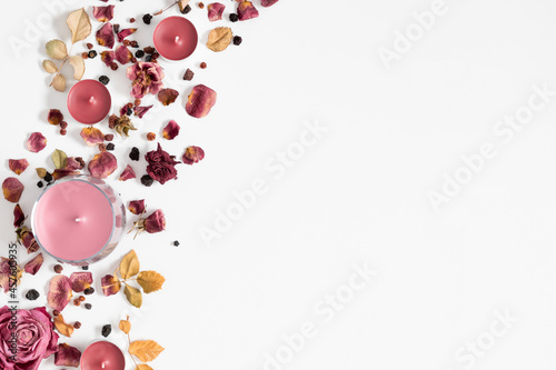 Autumn composition with dry roses and candles. Autumn background in pastel color with dried rose flowers and leaves. Flat lay, top view, copy space