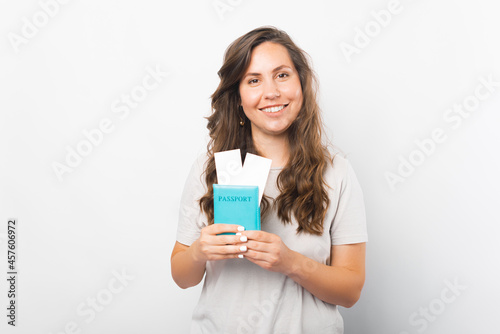Content young woman is holding passport with two tickets ready to travel over white background.