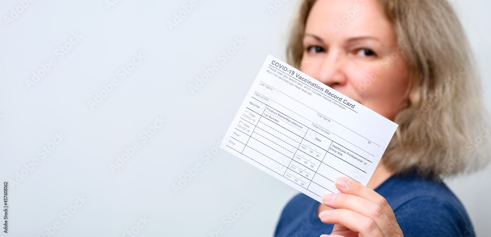 Young woman showing COVID-19 Vaccination Record Card. Vaccine theme for background. - obrazy, fototapety, plakaty 
