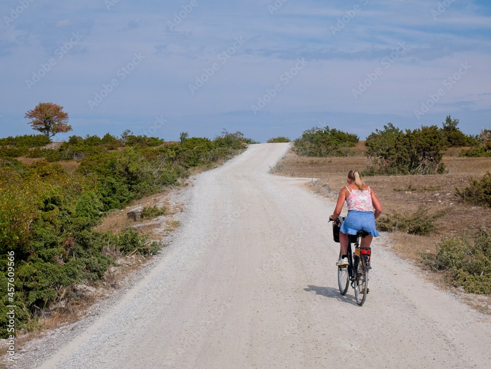 Blonde woman cycle on gravel road on Öland, Sweden. Blonde woman cycle on gravel road on Öland, Sweden.