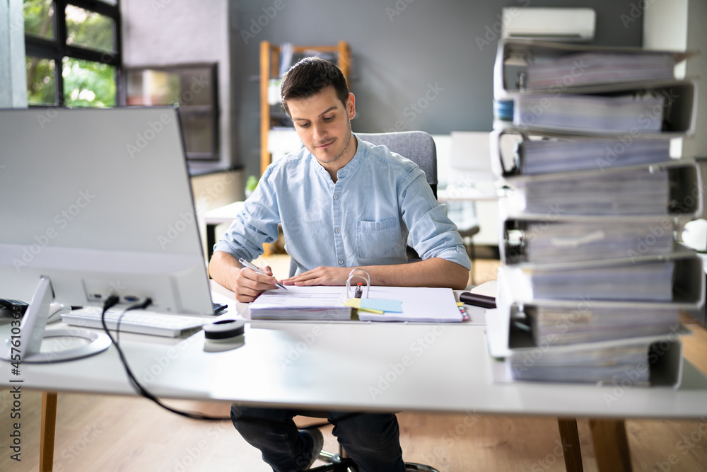 Young Businessman Working At Office With Stack Of Folders Young Businessman Working At Office With Stack Of Folders