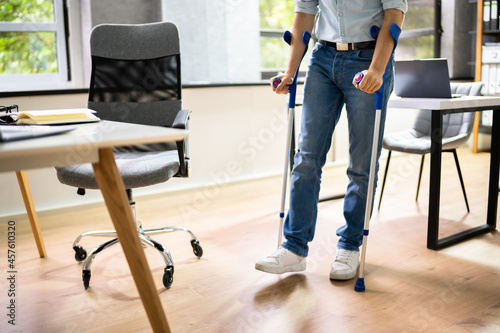 Worker With Crutches At Workplace Or Office