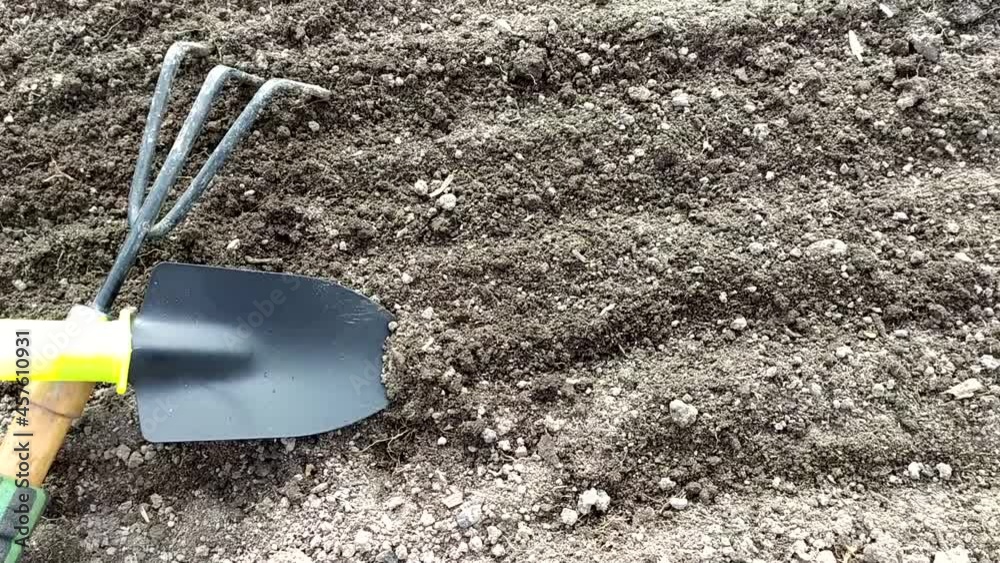 Dug up land in a greenhouse in a garden bed. Gardening tools on the surface of the earth. View from above.