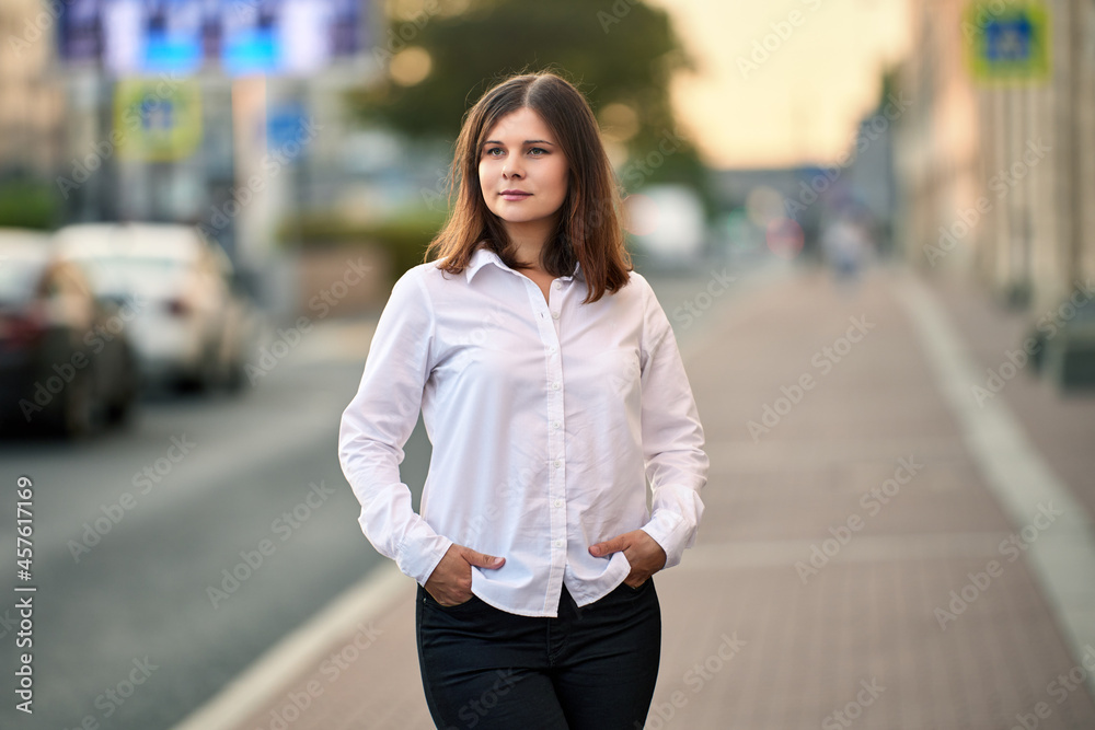 Woman 26 years old with brown hair stands on street.