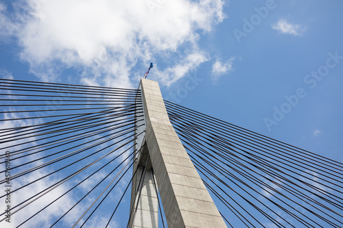 looking up bridge cables blue sky clouds concrete pylon construction build strong road structure engineering support photo