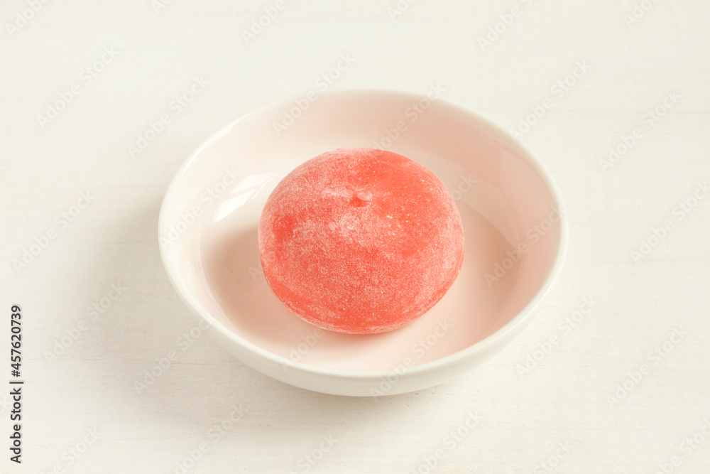 Pomegranate with honey Japanese dessert mochi on a small white bowl on a white wooden table. Closeup Pomegranate with honey Japanese dessert mochi on a small white bowl on a white wooden table. Closeup