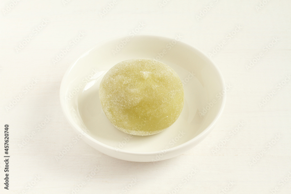 Green matcha tea Japanese dessert mochi on a small white bowls on a white wooden table. Closeup Green matcha tea Japanese dessert mochi on a small white bowls on a white wooden table. Closeup