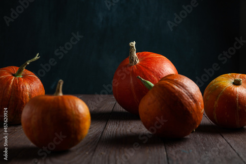 Five pumpkins on wooden table with dark background.