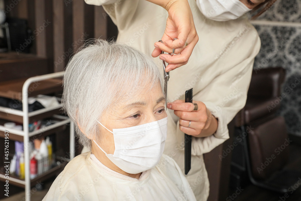 ヘアカットする美容師と高齢者女性