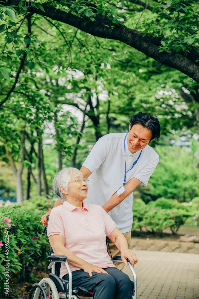 Fototapeta premium 車椅子に乗った高齢者女性と男性スタッフ