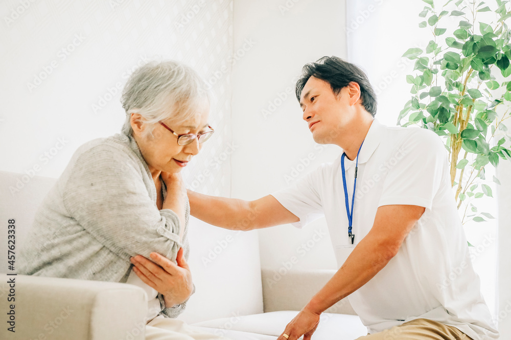 Obraz premium 訪問介護する男性と高齢者(肩こり)