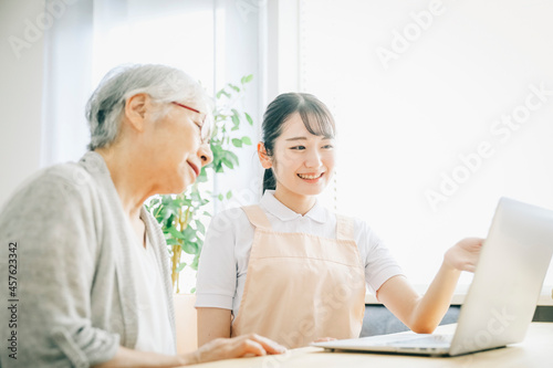 パソコンを使うエプロン姿の女性と高齢者（笑顔） 
