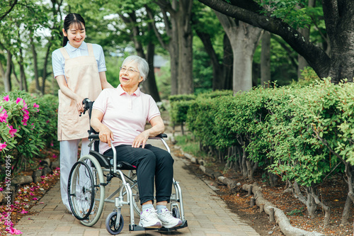 車椅子に乗った高齢者女性と女性スタッフ 
