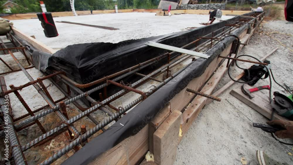 A worker is using a welding machine to put together two pieces of steel reinforcing. Sparks. Formwork preparation, temporary or permanent molds into which concrete is poured