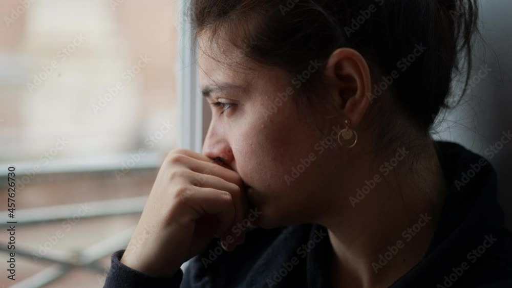 Pensive woman looking outside through window, thoughtful person thinking about life Pensive woman looking outside through window, thoughtful person thinking about life