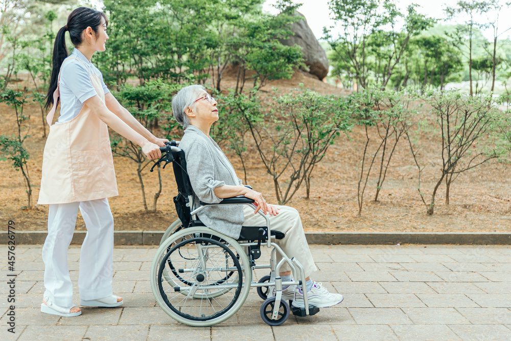 車椅子に乗った高齢者女性と女性スタッフ（横顔）

