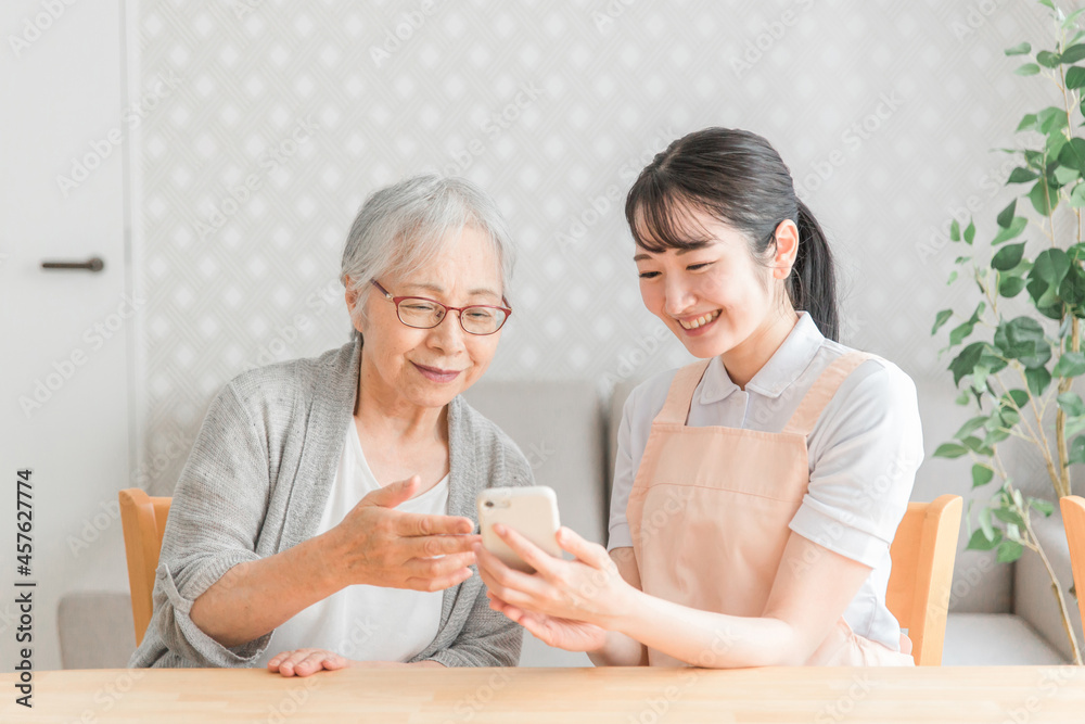 スマホを使う高齢者と女性スタッフ
