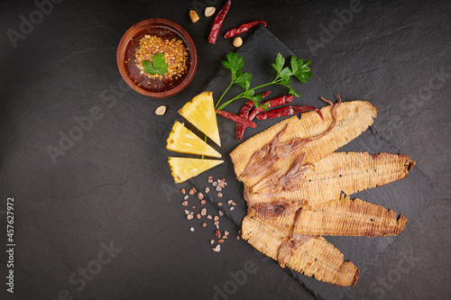 Grilled dried squid with sweet and sour sauce, Grilled dried squid with herbs and spices, various vegetables stone background, Mashed squid is materials raw from the sea, street food. Top view.