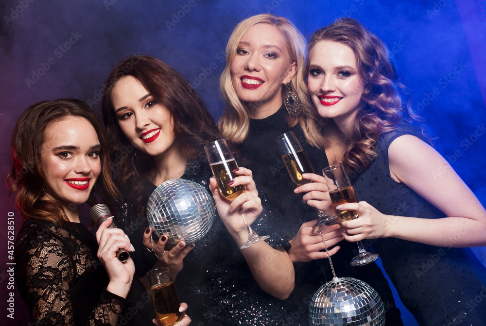 party and people concept - young women clinking flutes with sparkling wine over dark background.