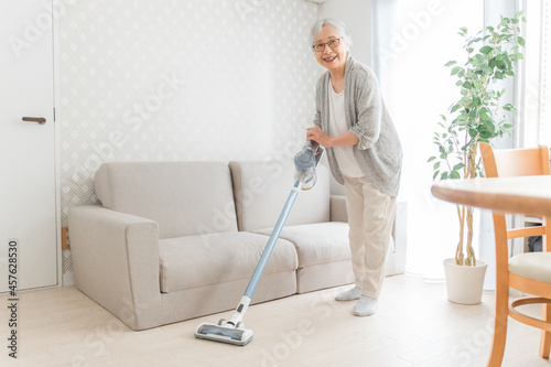部屋を掃除する高齢者女性（笑顔） 