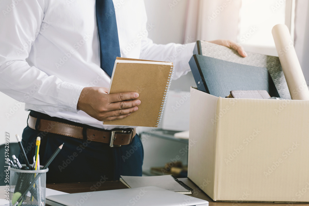 Resignation. businessman packing personal company belongings in a brown cardboard box when he deciding resignation and changing work in the future. Resignation. businessman packing personal company belongings in a brown cardboard box when he deciding resignation and changing work in the future.