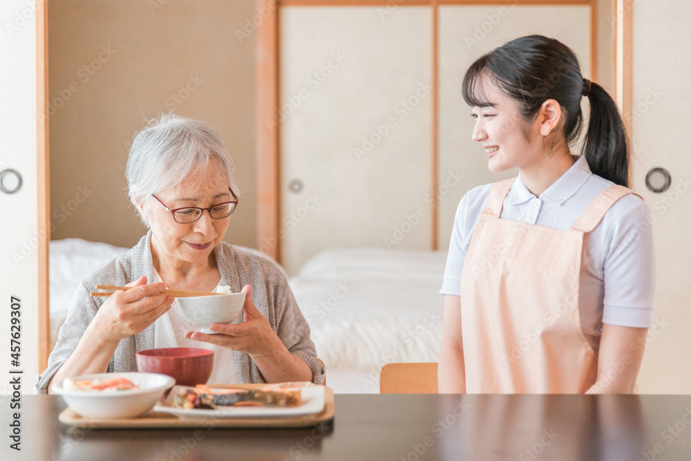 食事をする高齢者女性と女性スタッフ（笑顔）
