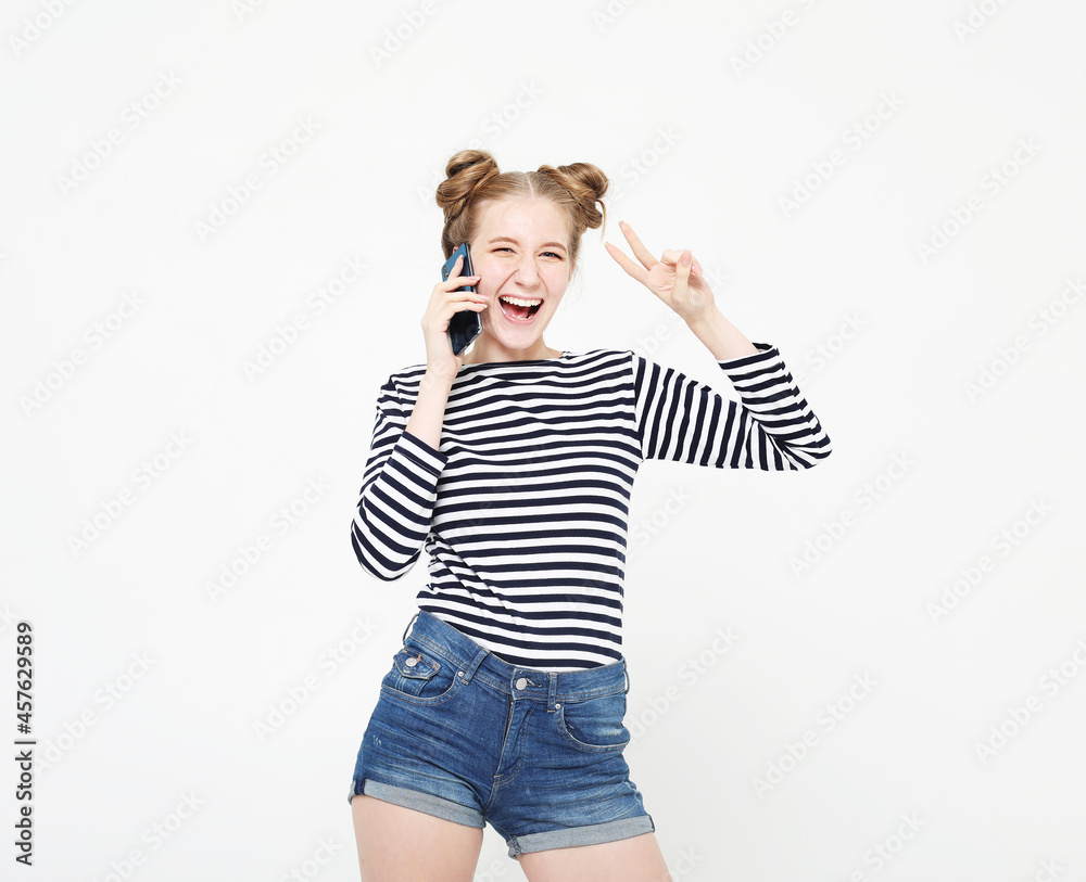 Beautiful woman wearing striped shirt talking on mobile phone and showing v-sign over white background Beautiful woman wearing striped shirt talking on mobile phone and showing v-sign over white background