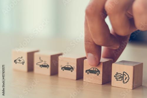 Artificial intelligence in autonomous car technology concept. A vehicle running self driving mode. Male hold wooden cube with autonomous car icon. Futuristic technology for the better human's life.